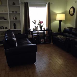 A cozy living room with leather sofas and a floor lamp by the window.