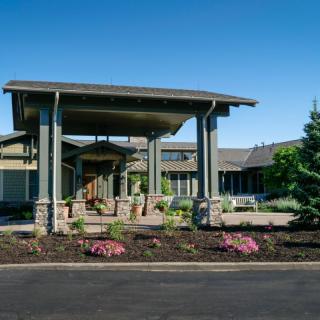 Entrance to a modern building with landscaped garden and covered driveway.