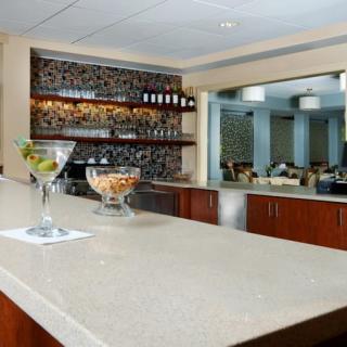 A modern bar setup with a cocktail on the counter and shelves stocked with bottles.