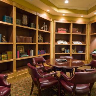 A cozy reading room featuring wooden bookshelves filled with various books and comfortable seating.