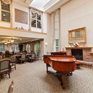 A spacious dining room with a grand piano, fireplace, and elegant seating arrangement.