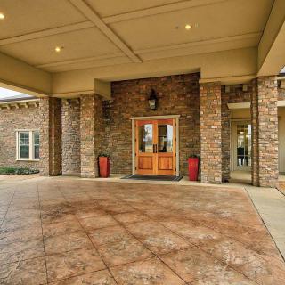 The image shows a building entrance with a stone facade and wooden doors, featuring a covered entryway.
