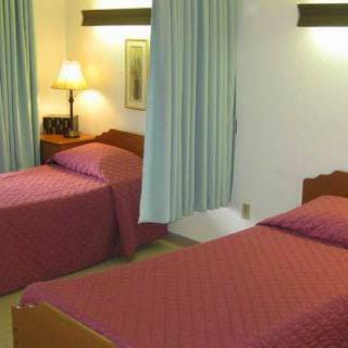 A cozy hotel room featuring twin beds with red bedding and a warm ambiance.