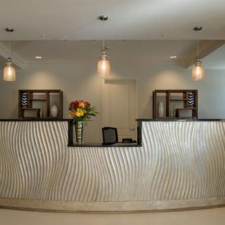 A modern reception desk with decorative lighting and a vase of flowers.