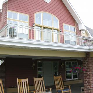 A two-story house with a balcony and rocking chairs on the porch.