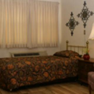 A cozy bedroom with a single bed, floral bedding, and decorative wall art.