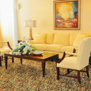 A cozy living room with a yellow sofa and armchairs, complemented by a wooden coffee table and floral decor.
