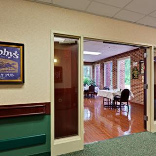 An inviting dining area with large windows and wooden flooring, featuring elegant table settings and a decorative poster on the wall.
