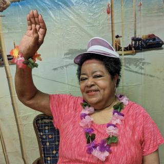 A joyful woman wearing a tropical hat and lei, celebrating in a festive atmosphere.
