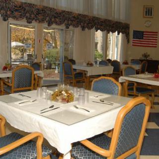 A neatly arranged dining room with tables set for a meal, featuring an American flag on the wall.