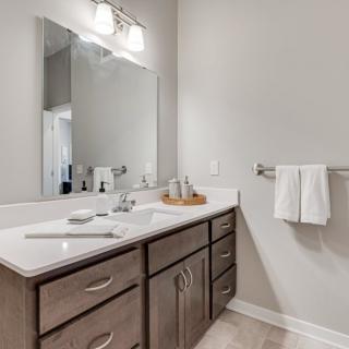 A modern bathroom with a large mirror and wooden vanity.
