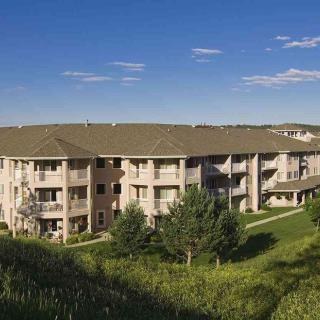 A scenic view of a residential apartment building surrounded by lush greenery and under a clear blue sky.