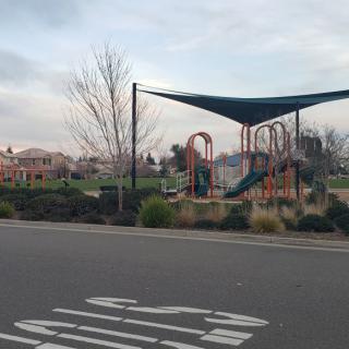 A playground with slides and shaded areas in a park setting.