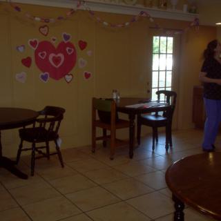 A cozy cafe interior featuring tables and chairs with heart-themed wall decorations.