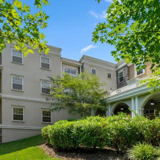 A residential building surrounded by trees and greenery on a clear day.