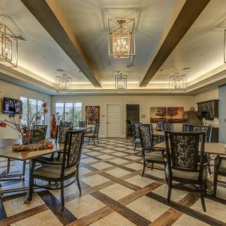 A spacious dining area with elegant chandeliers and neatly arranged tables and chairs.