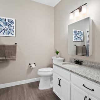 A modern bathroom interior featuring a toilet, sink, and mirror with stylish decor.