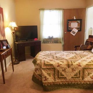 A cozy bedroom with a quilted bedspread, television, and warm lighting.
