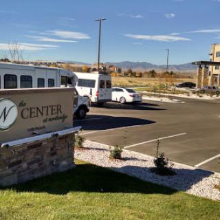 A view of the parking area and entrance sign for a center, with a bus and cars parked in the foreground.