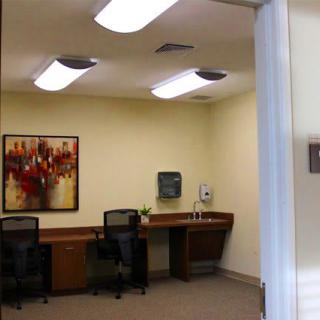 A modern office space with desks and chairs, adorned with artwork on the wall.
