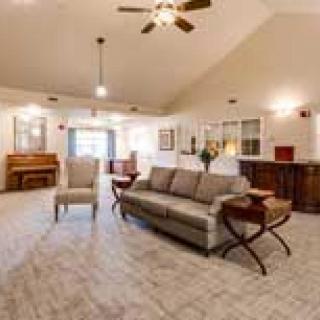 A spacious living room with a sofa, armchair, and ceiling fan, showcasing elegant interior design.