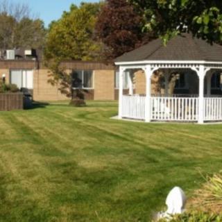 A well-maintained lawn with a white gazebo and surrounding buildings.