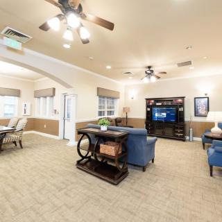 A cozy living room with comfortable furniture, a TV, and ample lighting.