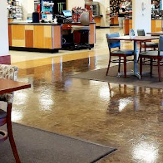 A spacious cafe interior featuring tables and chairs, a counter in the background, and polished floors.