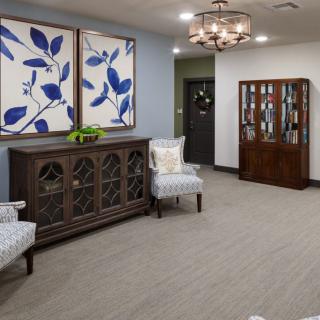 A modern lobby featuring elegant furniture, large botanical artwork, and a stylish chandelier.