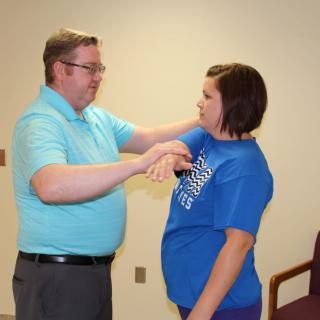 A therapist guides a woman through an arm exercise session.