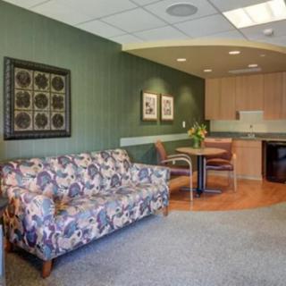 A cozy waiting room with a floral sofa, seating area, and wall art.
