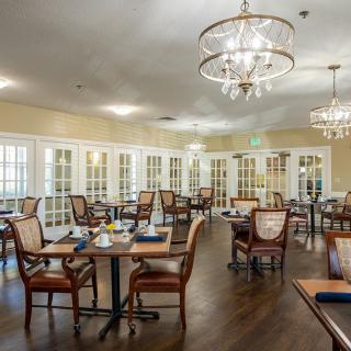 An elegant dining room with chandeliers and neatly arranged tables and chairs.