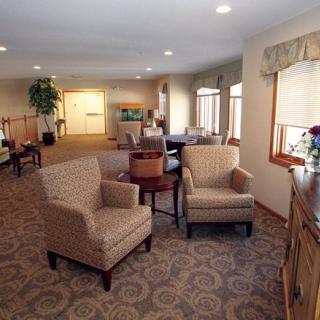 A well-furnished living room with comfortable chairs, tables, and a decorative carpet.