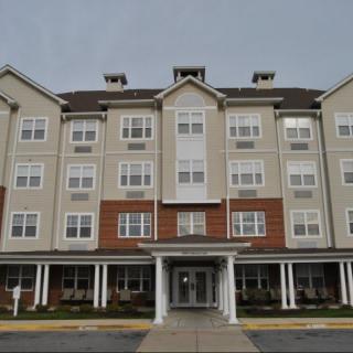 A multi-story residential building with a symmetrical facade and covered entrance.
