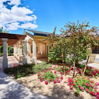 A beautiful house with a well-maintained garden full of colorful flowers under a clear blue sky.
