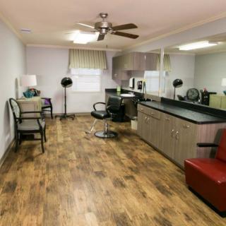 A spacious hair salon interior with wooden flooring, chairs, and large mirrors.