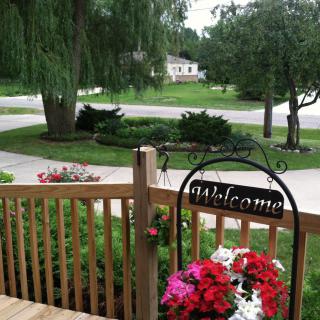 A charming porch with a welcome sign and vibrant flowers overlooking a suburban street.