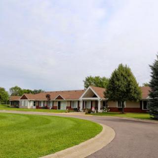 A serene residential area showcasing a single-story home surrounded by lush greenery and a winding driveway.