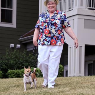 A woman walking her dog outside near a building.