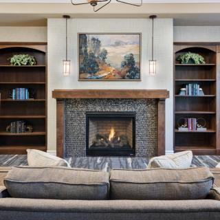 A cozy living room with a central fireplace, surrounded by built-in bookshelves and a comfortable couch.