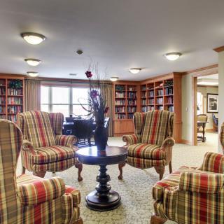 A cozy library lounge with armchairs and bookshelves.