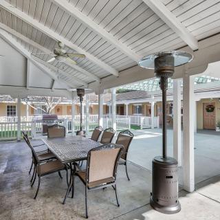 A covered outdoor patio with a dining table, chairs, and a heater.