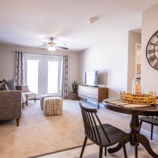 A modern living room and dining area with natural light and cozy furnishings.