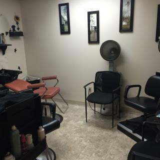 A cozy salon interior featuring multiple chairs, a hair dryer, and decorative wall art.