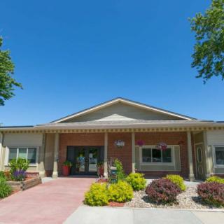 A front view of a single-story building with landscaped surroundings under a clear blue sky.