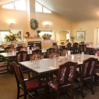 A well-lit dining room with neatly arranged tables and chairs, decorated with plants and wall art.