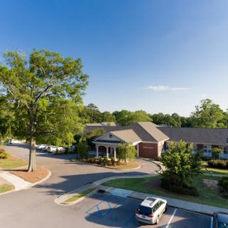 A tranquil residential building surrounded by greenery and a clear blue sky.