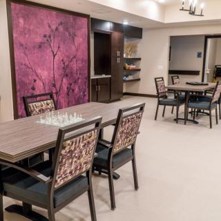 A modern dining area featuring tables with chessboards, surrounded by stylish chairs and a large, colorful piece of artwork on the wall.