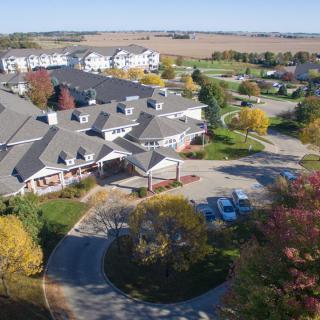Aerial view of a suburban residential area with buildings surrounded by autumn trees and roads.