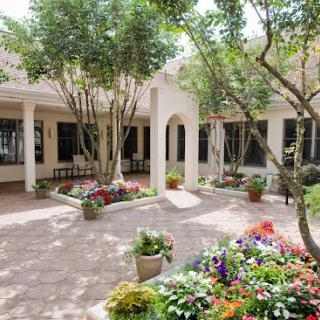 A serene courtyard filled with vibrant flowers and lush greenery.